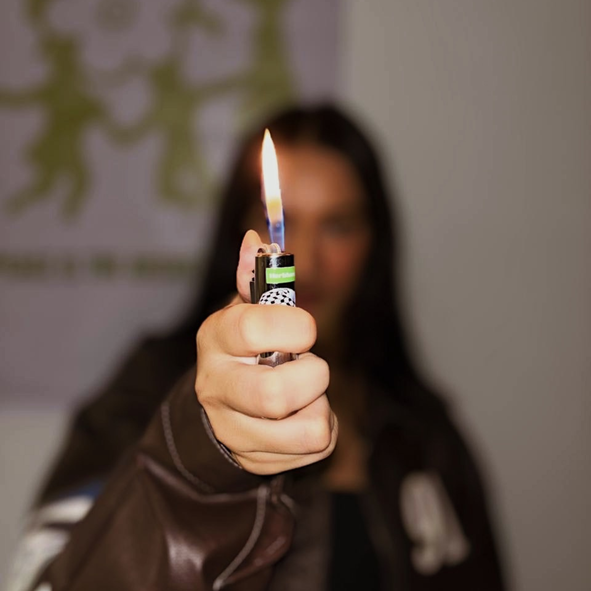 Person holding a herblunt lit lighter with a blurred background